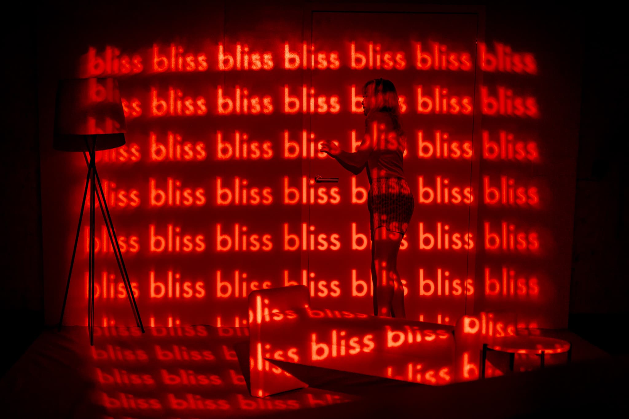 A performer silhouetted against repeated red text