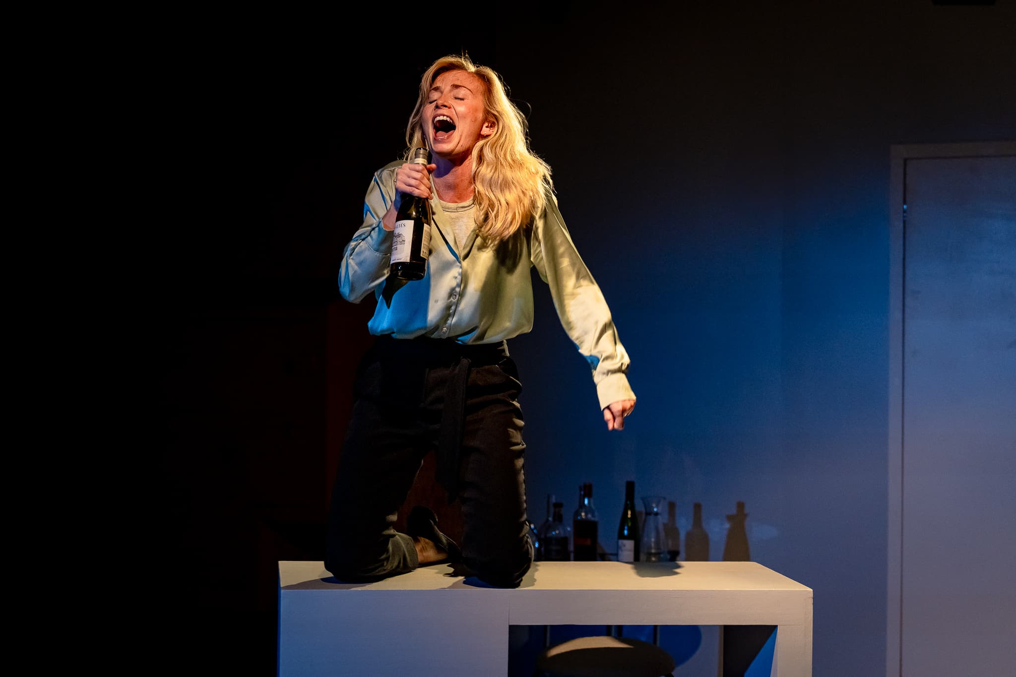 A performer standing beneath stark stage lighting