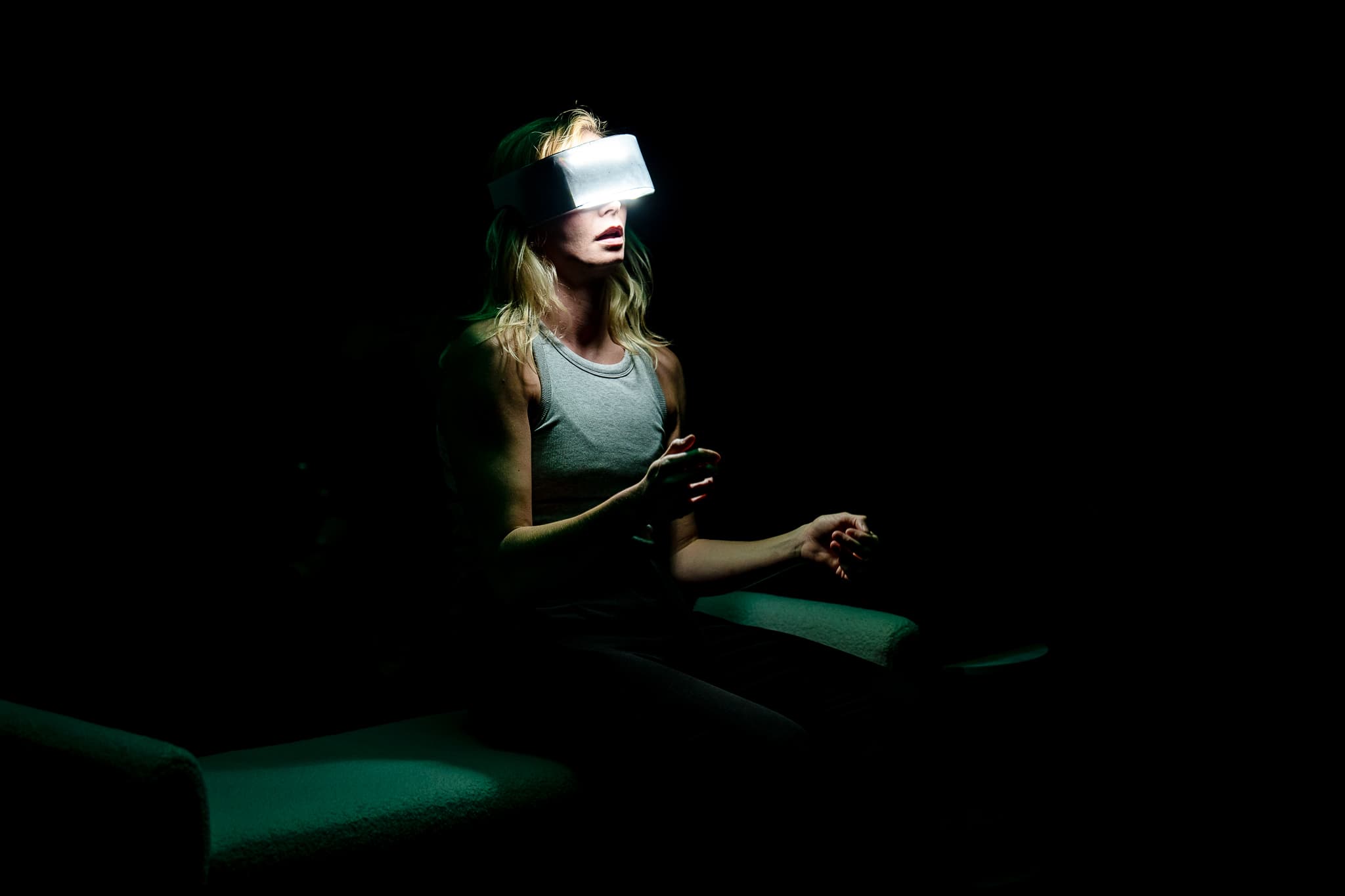 A performer wearing a glowing digital visor in darkness