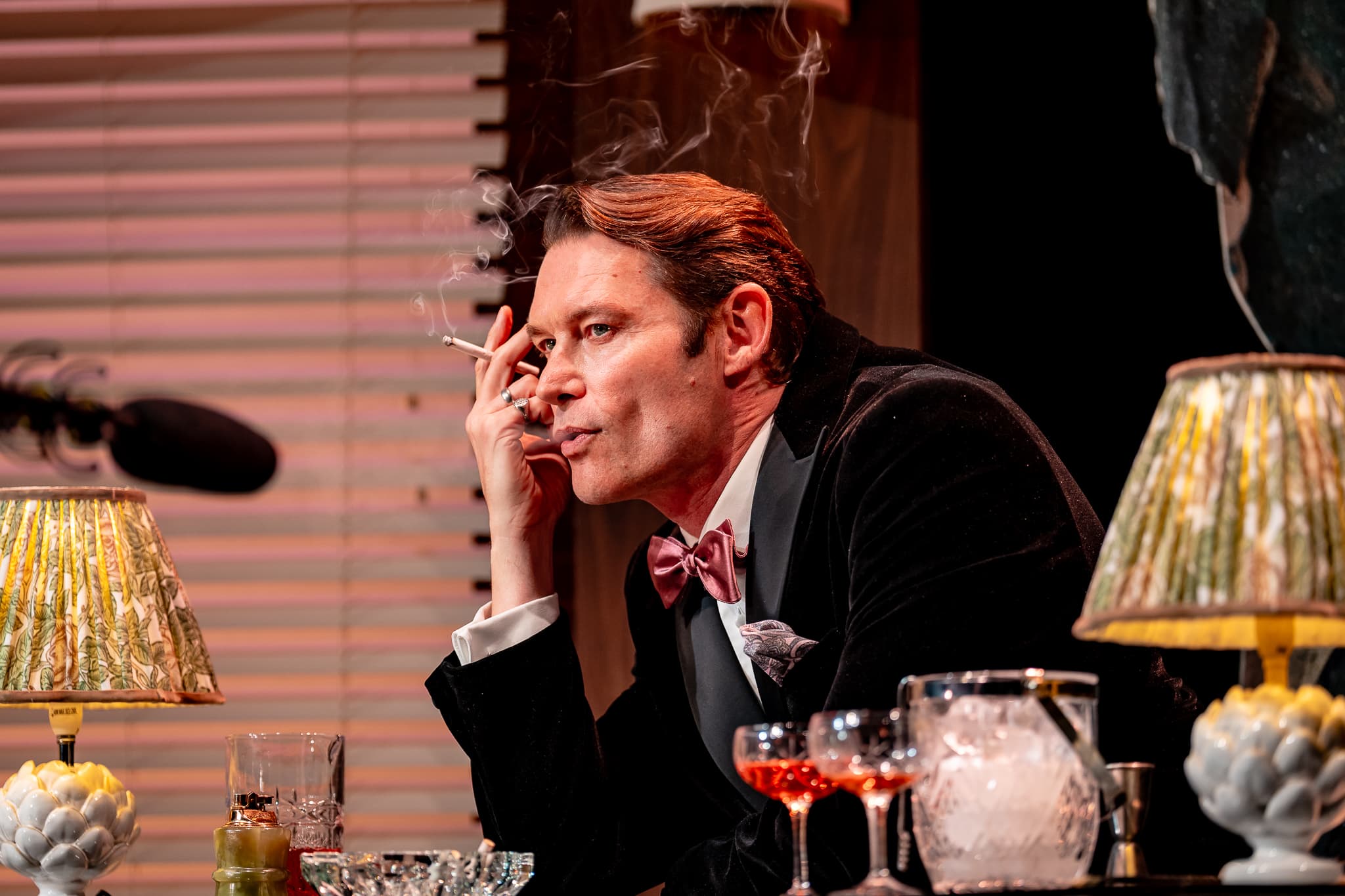 A performer seated at a drinks trolley during The Code